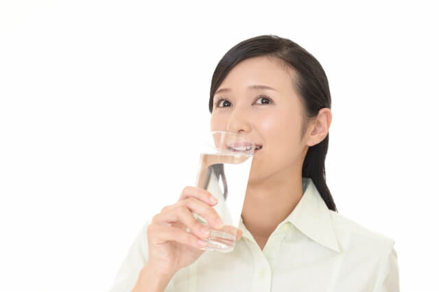 グラスで水を飲んでいる女性