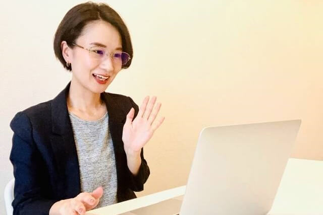 笑顔でパソコンでオンライン通話をしている女性